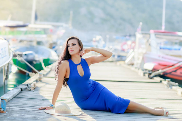 A woman in a blue dress model lies on the pier for boats - Фото, изображение