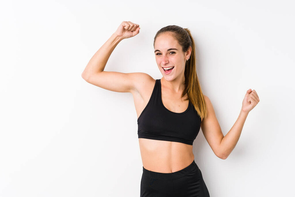 Young caucasian fitness woman posing in a white background celebrating a special day, jumps and raise arms with energy. - Photo, image