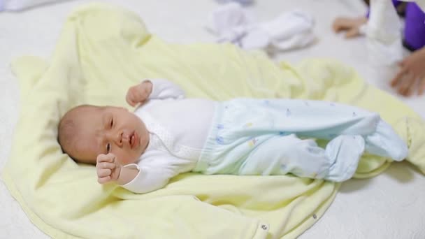 Mamá viste a un bebé recién nacido con un traje blanco
 - Imágenes, Vídeo
