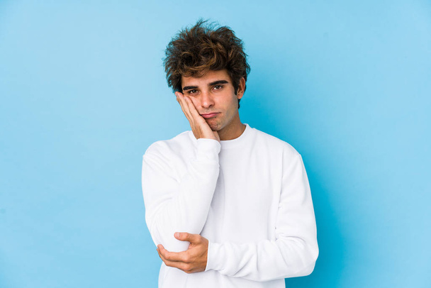 Young caucasian man against a blue background isolated who is bored, fatigued and need a relax day. - Photo, Image