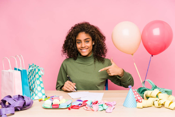 Young african american woman planning a birthday person pointing by hand to a shirt copy space, proud and confident - Photo, Image