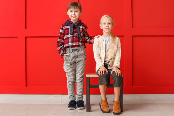 Bambini piccoli e carini in abiti autunnali vicino alla parete di colore
 - Foto, immagini