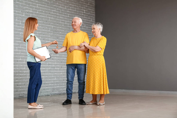 Real estate agent giving a key from new house to senior couple - Photo, Image