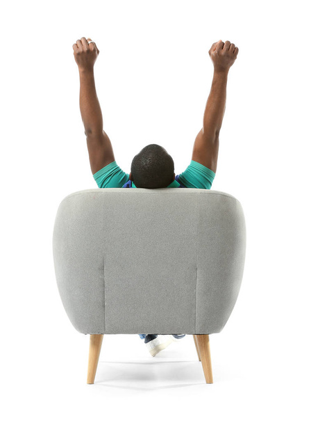 Hombre afroamericano relajándose en sillón sobre fondo blanco, vista trasera
 - Foto, imagen