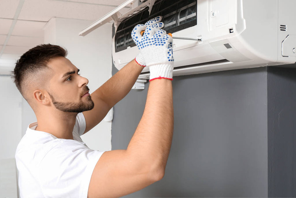 Técnico masculino reparando aire acondicionado en interiores
 - Foto, Imagen