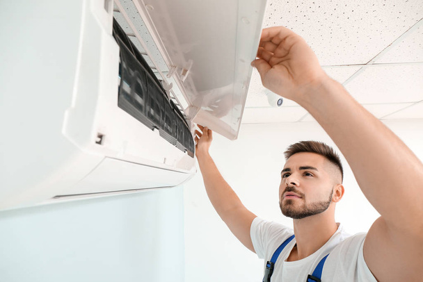 Technicien masculin réparant climatiseur intérieur
 - Photo, image