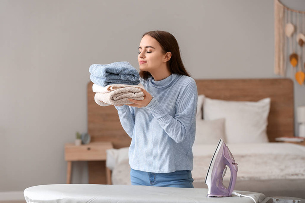 Mulher bonita com lavandaria engomada limpa em casa
 - Foto, Imagem