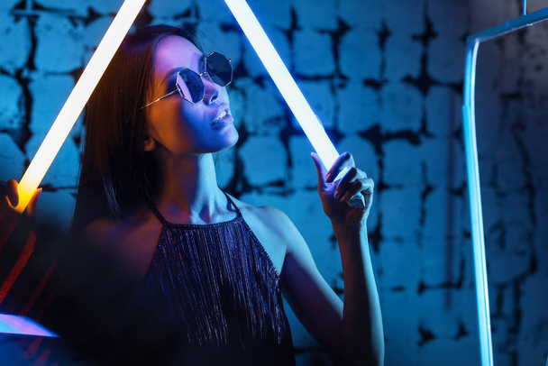 getöntes Porträt einer schönen Frau mit Neonlampen auf dunklem Hintergrund - Foto, Bild