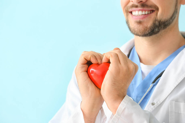 Male cardiologist with red heart on color background, closeup - Photo, Image