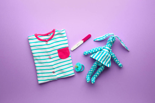 Pregnancy test, baby clothes and toy on color background - Photo, Image