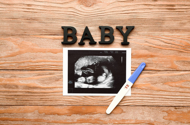 Pregnancy test, word BABY and sonogram image on wooden background - Photo, Image