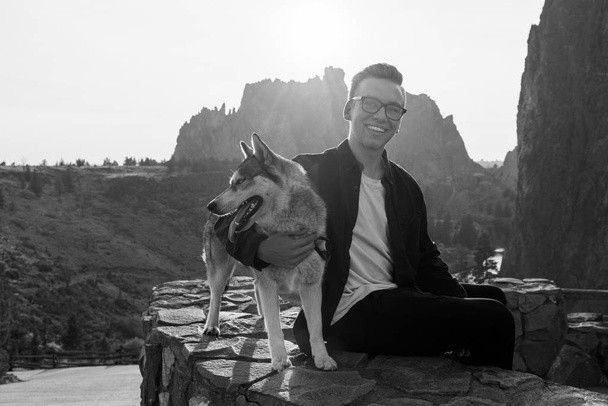Молодий чоловік зі своїм гамірним собакою насолоджується заходом сонця в парку "Сміт - Рок". - Фото, зображення