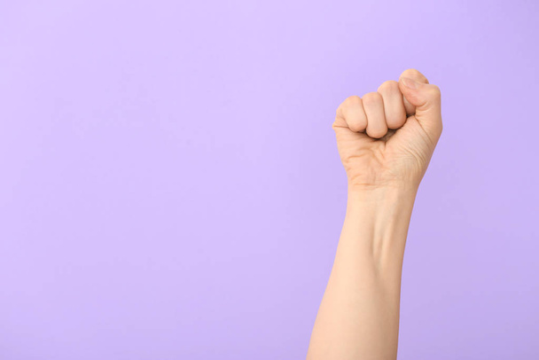 Рука женщины с сжатым кулаком на цветном фоне
 - Фото, изображение