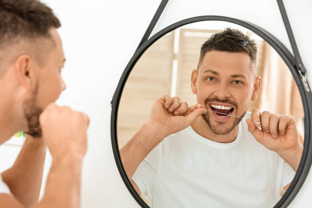 Handsome man flossing teeth at home - Photo, image