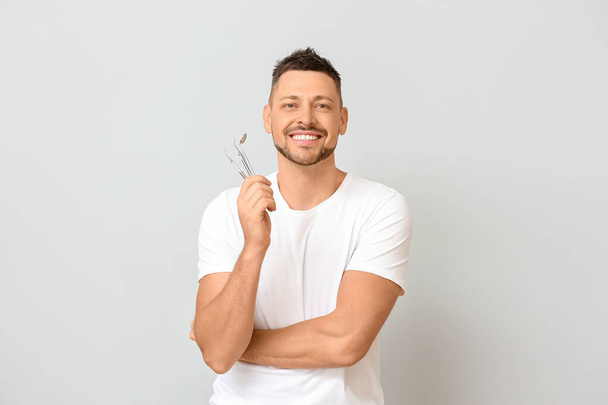 Mann mit Zahnwerkzeug auf hellem Hintergrund - Foto, Bild