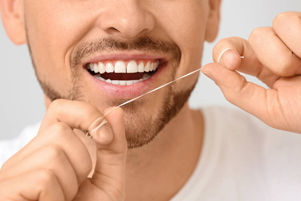 Przystojny mężczyzna nici dentystyczne zęby na szarym tle, zbliżenie - Zdjęcie, obraz