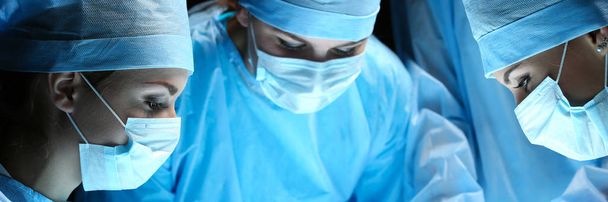 Groupe de chirurgiens au travail opérant en salle d'opération
 - Photo, image