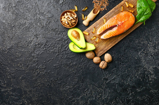 Conjunto de productos saludables con alto contenido de omega 3 y píldoras de aceite de pescado sobre fondo oscuro
 - Foto, imagen