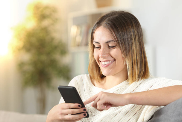 Happy girl uses smart phone at home - Foto, imagen