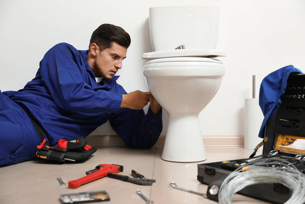 Επαγγελματίας υδραυλικός που εργάζεται με λεκάνη τουαλέτας στο μπάνιο - Φωτογραφία, εικόνα