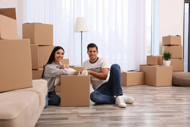 Happy couple unpacking cardboard boxes in their new flat on movi - Фото, зображення
