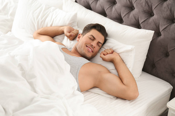 Man awakening on bed at home. Lazy morning - 写真・画像