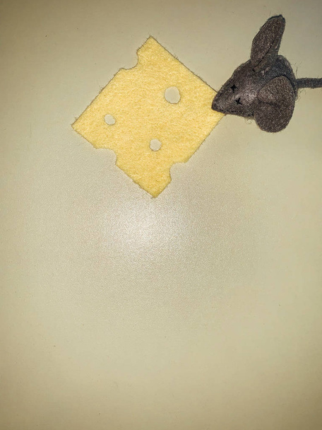 zacht muisspeelgoed met gele kaas op een grijze achtergrond - Foto, afbeelding