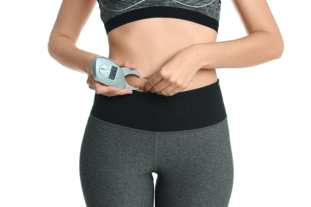 Young woman measuring body fat with caliper on white background, closeup - Foto, Bild