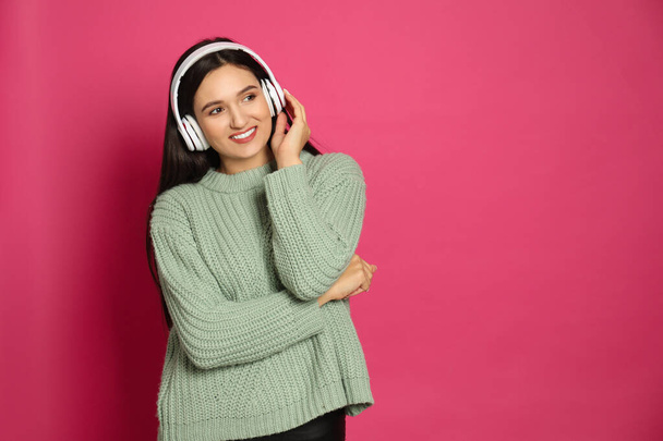 Young woman listening to audiobook on pink background. Space for text - Foto, Bild