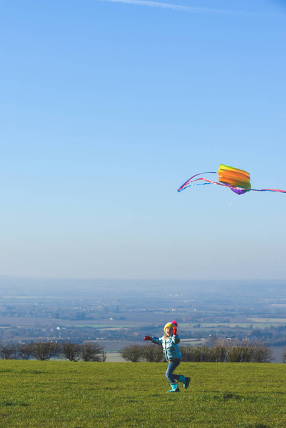 Child flying a kite outdoors on a sunny clear day in a country f - Zdjęcie, obraz
