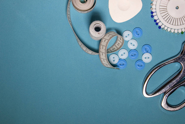 Naai accessoires en stof op een blauwe ondergrond. naaigarens, naalden, spelden, weefsel. - Foto, afbeelding