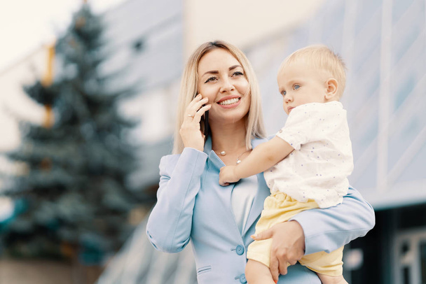 Onnistunut liiketoiminnan nainen sininen puku vauvan kanssa muotokuva
 - Valokuva, kuva