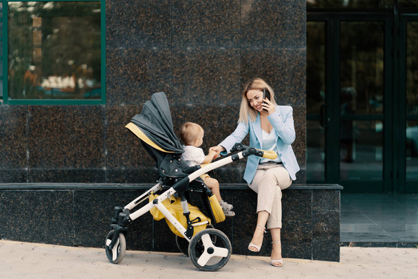 Portrait of a successful business woman in blue suit with baby - 写真・画像