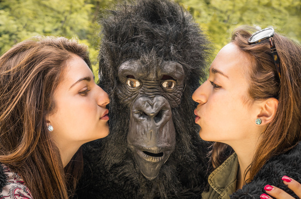 Две девушки целуют изумленную гориллу
 - Фото, изображение