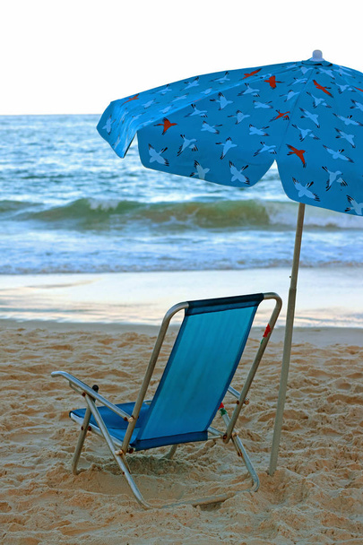 lebendige blaue Liegestühle mit Sonnenschirm am Sandstrand mit Blick auf den Atlantik - Foto, Bild