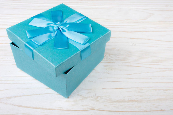 Μπλε κουτί δώρου στο λευκό ξύλινο φόντο (αντίγραφο χώρου για το κείμενό σας) - Φωτογραφία, εικόνα