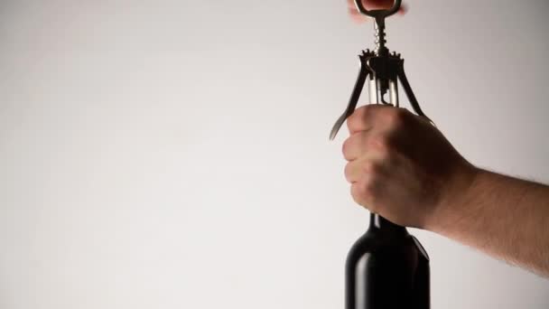 Sommelier opening red wine bottle on white background. Man hands pulling cork out of the bottle using opener - Metraje, vídeo