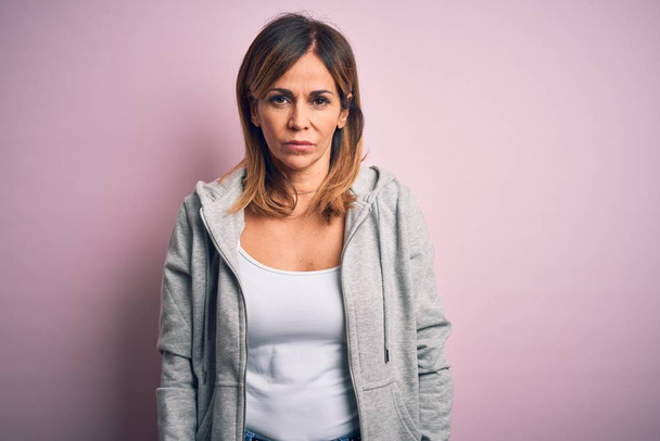 Middle age beautiful sportswoman wearing casual sweatshirt over isolated pink background with serious expression on face. Simple and natural looking at the camera. - Foto, imagen