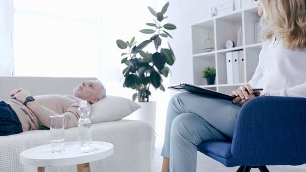 cropped view of psychologist talking to patient lying on couch - Materiaali, video