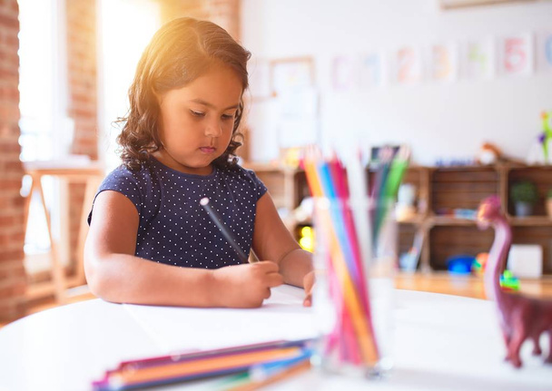 Hermosa niña dibujo lindo dibujo utilizando lápices de colores en el jardín de infantes
 - Foto, Imagen