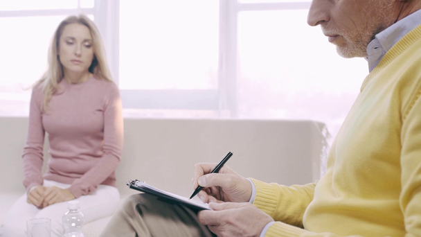 cropped view of mature psychologist writing prescription while talking to patient - Footage, Video