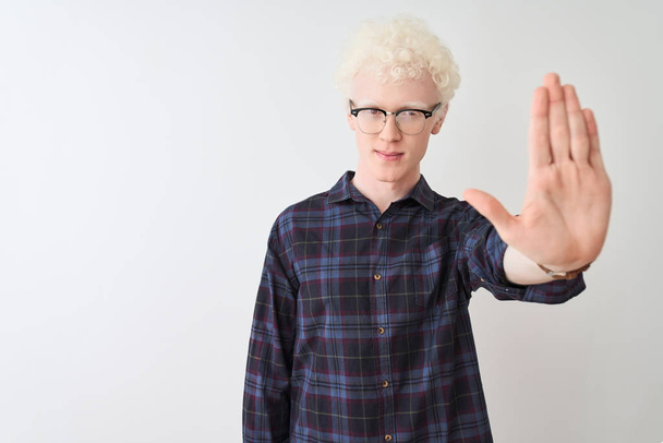 Nuori albiino vaalea mies yllään rento paita ja lasit yli eristetty valkoinen tausta tekee lopettaa laulaa kämmenellä. Varoituksen ilme negatiivisella ja vakavalla eleellä kasvoilla
. - Valokuva, kuva