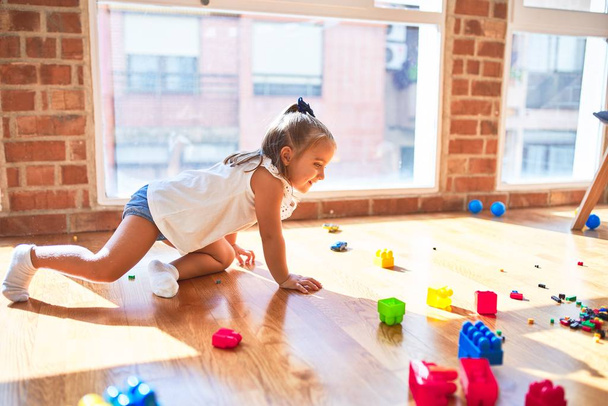 Молода красива блондинка дитина насолоджується грою в школу з іграшками в дитячому садку, посміхаючись щасливою грою вдома
 - Фото, зображення