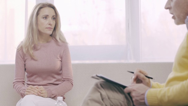 psicólogo maduro segurando prancheta e falando com o paciente
 - Filmagem, Vídeo