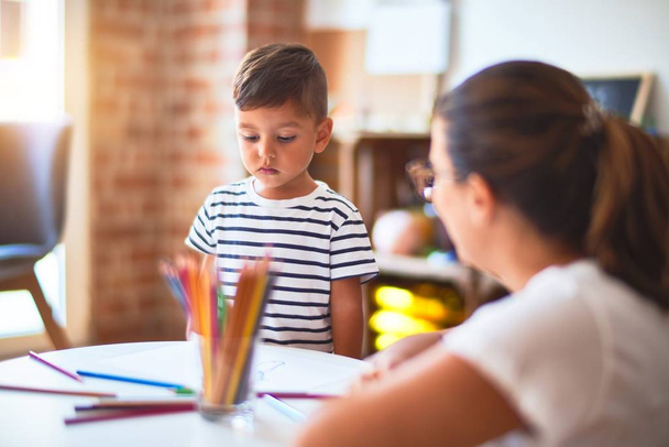 Kaunis opettaja ja lapsi poika piirustus piirtää käyttäen värillisiä kyniä päiväkodissa
 - Valokuva, kuva