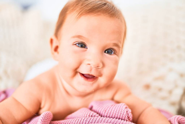 Evdeki güzel bebek kanepeye uzanmış mutlu bir şekilde gülümsüyor. Yüzünde gülümsemesi olan yeni doğmuş bir bebek. Rahatlıyor ve dinleniyor. - Fotoğraf, Görsel
