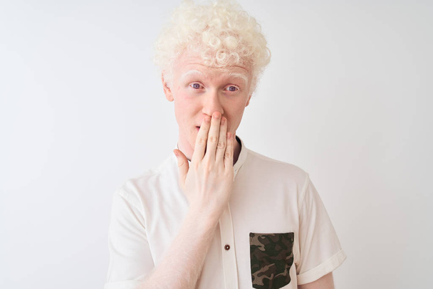 Young albino blond man wearing casual shirt standing over isolated white background cover mouth with hand shocked with shame for mistake, expression of fear, scared in silence, secret concept - Foto, Bild