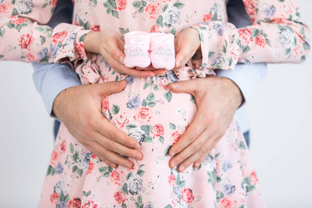 Young pregnant woman holding baby booties - Gender Reveal - It's - Φωτογραφία, εικόνα