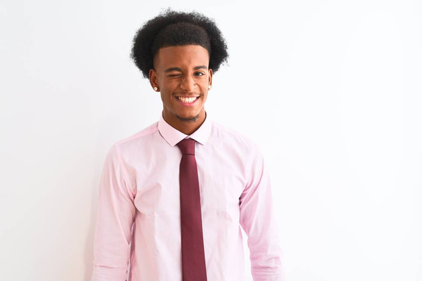 Νεαρός Αφροαμερικάνος επιχειρηματίας με γραβάτα στέκεται πάνω από απομονωμένο λευκό φόντο κλείνει το μάτι κοιτάζοντας την κάμερα με σέξι έκφραση, χαρούμενο και χαρούμενο πρόσωπο. - Φωτογραφία, εικόνα