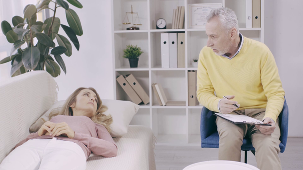 zralé psycholog mluví s pacientem ležícím na gauči - Záběry, video